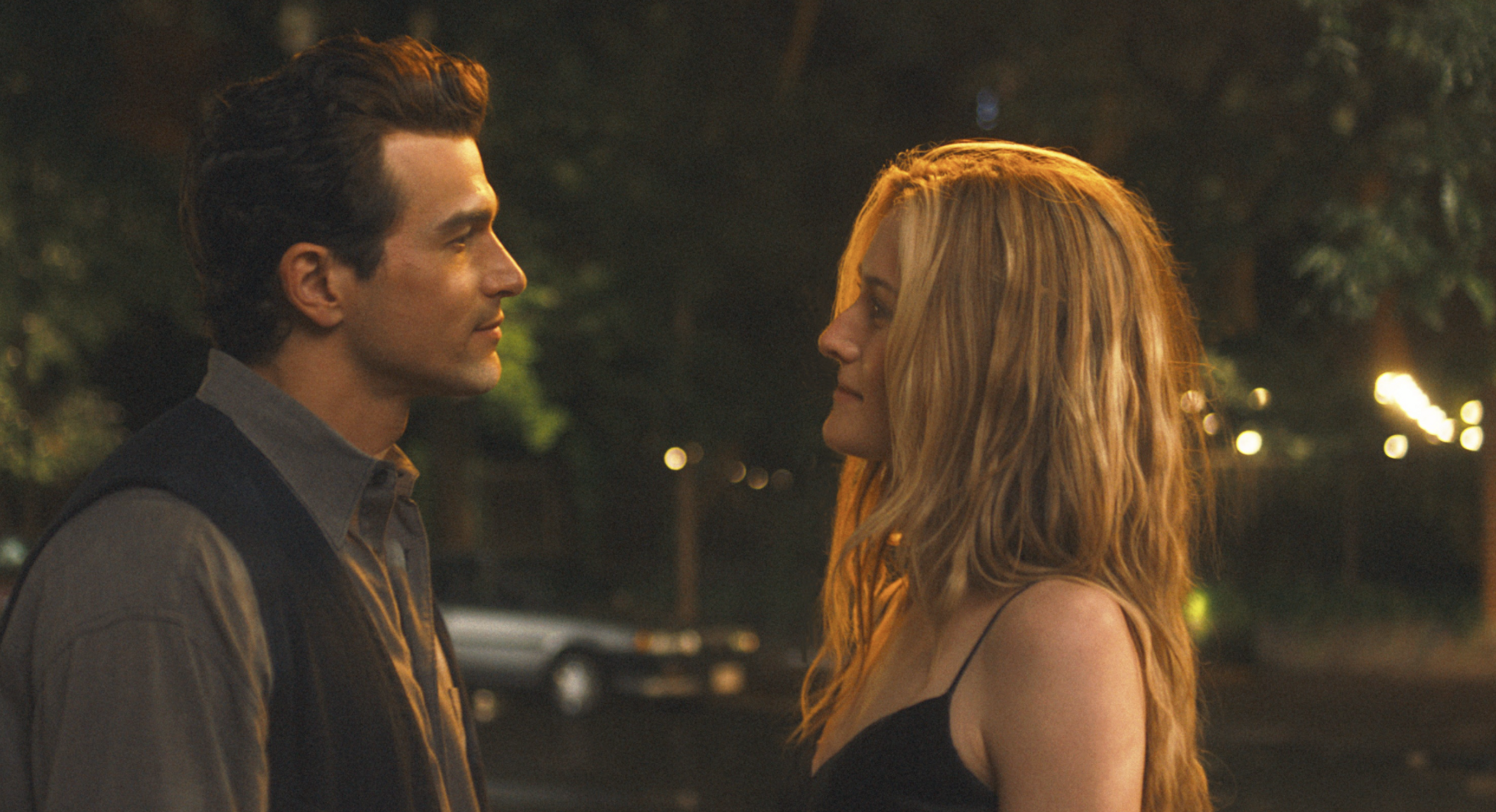 &laquo; Photographie de l'actrice Sarah Pidgeon incarnant Carolyn Bessette dans la s&eacute;rie "Love Story" de Disney+, diffus&eacute;e en f&eacute;vrier 2026. Elle porte la robe nuisette (slip dress) noire satin&eacute;e de Calvin Klein, pi&egrave;ce culte des ann&eacute;es 90 qui a g&eacute;n&eacute;r&eacute; un pic de recherche Google de +280 %. Le plan illustre le minimalisme chic et le "Quiet Luxury" de la maison de couture. &raquo;